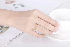 Dettaglio dell'anello a catena dorato con resina rossa indossato sulla mano in stile minimalista