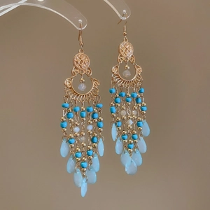 Detail of bohemian drop earrings with turquoise beads and gold metal tassels on hooks