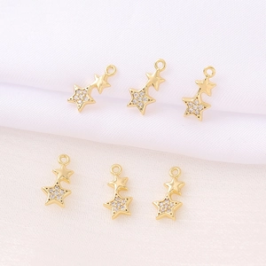 Golden double star pendants with zircon crystals and connecting rings on white background