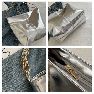 Detail view of silver tote bag with gold chain strap and zipper on white fabric
