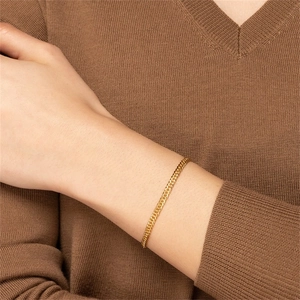 Close-up of a gold-plated stainless steel curb chain bracelet worn on a female wrist