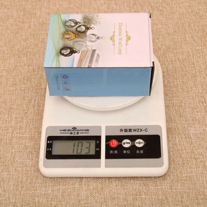 Close-up of the 103g festive electronic wind lamp gift packaging on a digital scale