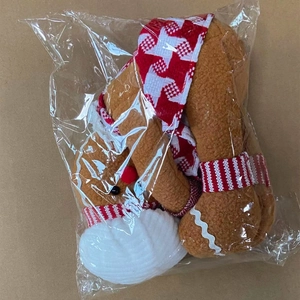 Detail of gingerbread man plush bottle cover in clear plastic packaging on cardboard