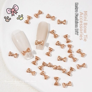 Close-up of mini 3D metal bow tie nail charms in rose gold for manicure DIY decor