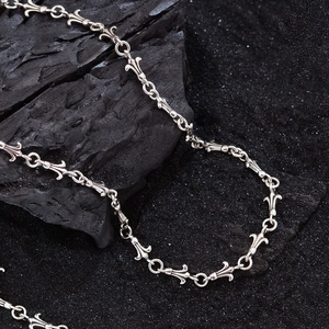 Vintage gothic fleur-de-lis silver chain necklace with cross link design on dark background