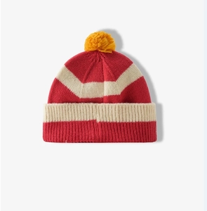 Detail van rood en beige gestreepte gebreide textuur met een gele pluizige pompon