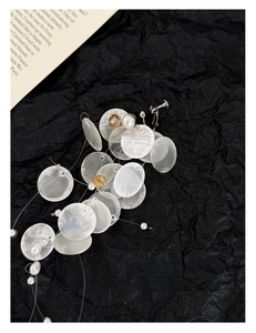 Detail of round shell petal earrings with white pearls and gold crystal beads on black background