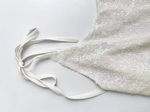 Détails de sequins irisés et de fines bretelles sur une robe de vacances en résille blanche