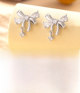 Detail of silver bow stud earring with white zircon inlay and titanium steel screw back