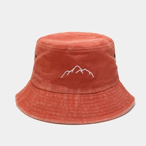 Macro detail of mountain peak embroidery on washed brick red cotton bucket hat