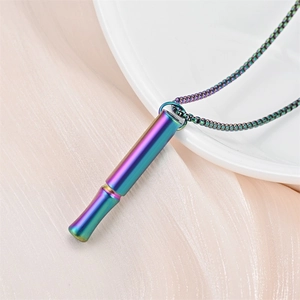 Detailed view of a rainbow iridescent mindfulness breathing whistle necklace on soft fabric