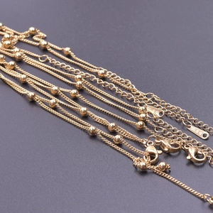 Detailed macro shot of 18k gold-plated stainless steel bead chains with S.STEEL stamp