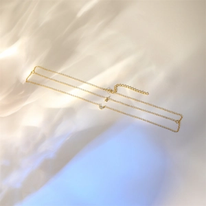 Close-up of gold layered heart and star necklace with zircons on white silk background