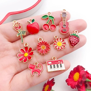 Handheld assorted red enamel alloy charms including flowers, fruit, and guitar shapes