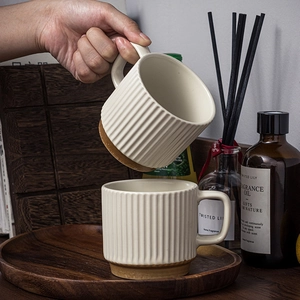 Minimalist beige ceramic mugs with vertical stripes on a wooden tray in a cozy home setting