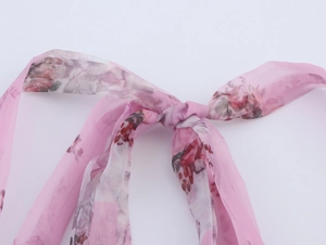 Detail view of pink floral chiffon halter dress featuring a delicate ribbon bow accent
