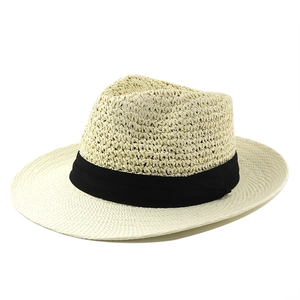 Close-up of a beige straw hat with black ribbon, featuring fine woven texture and brim