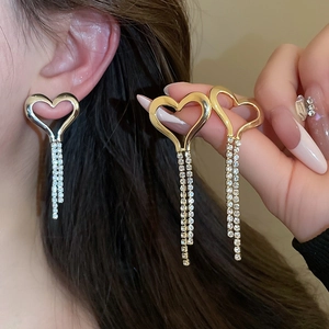 Detail view of gold and silver tassel heart earrings with rhinestones on model
