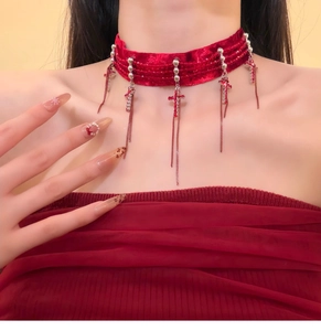 Detail of red velvet choker with silver beads, red cross pendant and long metal tassels