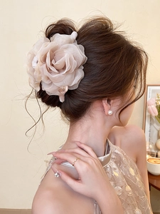 Detail of elegant champagne fabric rose hair claw clip on woman's back bun hairstyle
