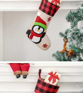 Detail of hanging Christmas stocking with penguin embroidery on rustic burlap fabric