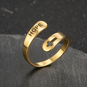 Macro detail of gold stainless steel ring with HOPE engraving and cross cutout