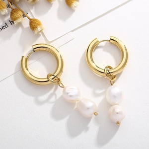 Détail de boucles d'oreilles élégantes à double perle avec créoles dorées sur blanc