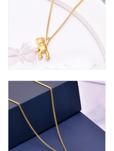 Detail of 3D polished golden bear pendant necklace on marble and jewelry box