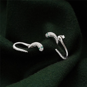 Macro view of 925 silver snake earrings with white zircons and green gemstone eyes