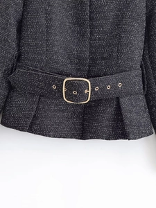 Close-up of black tweed jacket waist featuring a belt with a gold square metal buckle
