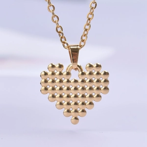 Close-up of golden pixelated heart pendant necklace with metallic sphere texture