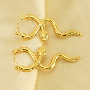 Detail of gold snake hoop earrings featuring an intertwined serpent design on satin