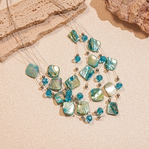 Detail of multi-strand layered necklace with blue crystal beads and iridescent shell slices