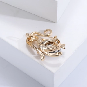 Close-up of golden cat brooch back showing needle pin and dark crystal inlays