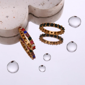 Close-up of 18K gold plated rings with colorful zircon insets on a water reflective surface