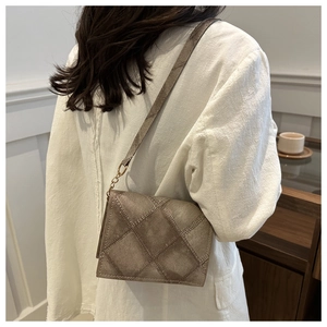 Detail shot of a quilted cross-body square bag with vintage texture and golden chain strap