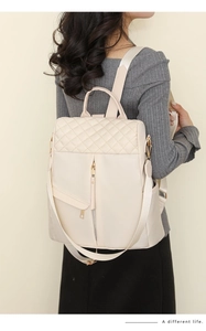 Detail of beige quilted nylon backpack featuring diamond stitching and gold-tone hardware