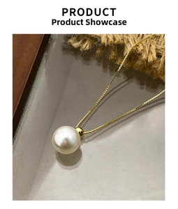 Detail view of large white round pearl pendant on elegant golden box chain necklace