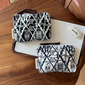 Detailed close-up of intricate embroidery on cotton linen coin purses with metal zippers