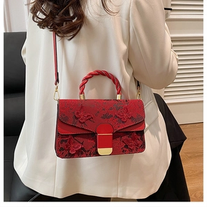 Detailed view of red handbag with butterfly embroidery and braided chain handle