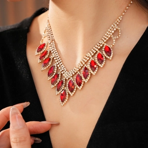 Detail of V-shaped gold necklace with red leaf gems and crystals on a model