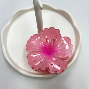 Close-up of pink acrylic flower hair claw clip on white pedestal for beach vacation
