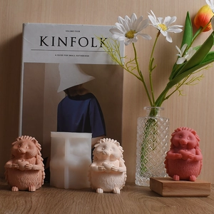 3D hedgehog silicone mold with finished wax candles on a wooden desk with flowers