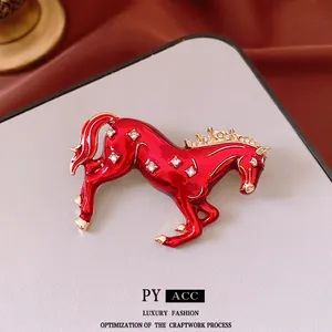 Chinese style red enamel horse brooch with crystals in gold finish on a display card