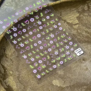 Dettaglio di adesivi floreali ultra sottili per unghie con motivi a cuore rosa e viola
