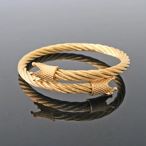 Macro detail of golden cable twisted cuff bracelet with ornate royal crown terminals