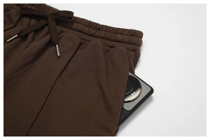 Detail of high-waist elastic waistband with drawstring and large pocket holding a phone