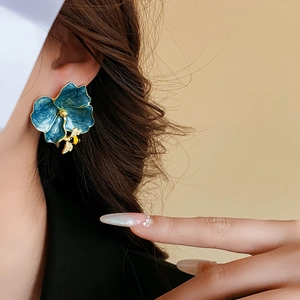 Detail of vintage blue enamel flower earring with gold bee on a model ear