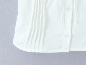 Detailed macro view of white pleated woven fabric with vertical pintucks and clear button