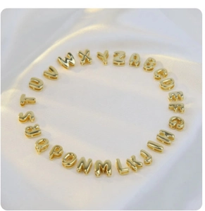 Macro shot of gold bubble alphabet beads A to Z arranged in a circle on white silk fabric